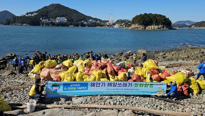 지난 3일 2026여수세계섬박람회 D-300 기념 해양 정화활동에 참여한 시민들이 돌산읍 외치도 해안에서 수거한 해양쓰레기와 함께 기념촬영을 하고 있다.