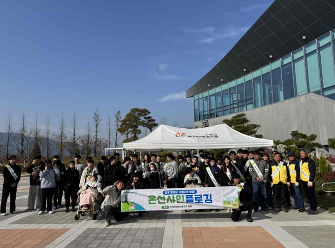 밀양시시설관리공단과 김해 은혜학교 학생들이 선샤인 밀양 테마파크 일대에서 환경정화 활동 후 단체 기념 촬영을 하고 있다